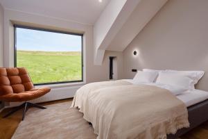 a bedroom with a large window and a bed and a chair at Tindasel - The Farm in Hella
