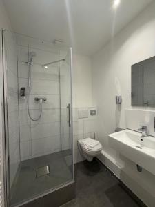 a bathroom with a shower and a toilet and a sink at URBAN OAK Smart Stay in Cologne