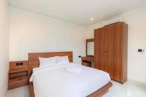 a bedroom with a white bed and a wooden cabinet at Villa didi By sedana cottage in Pererenan +32 photos