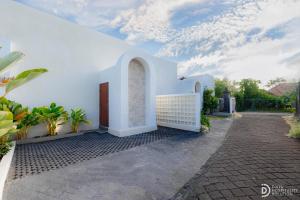 a white building with a door and some plants at Villa didi By sedana cottage in Pererenan