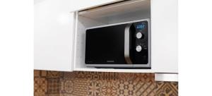 a microwave oven in a white cabinet in a kitchen at Doux Pavillon - La Palmeraie in Nice
