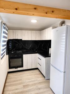 a kitchen with a white refrigerator and black counter tops at A Frame YRA cu ciubar in Câmpulung