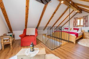 a attic bedroom with a bed and a red chair at Haus Sunnseit'n in Pöllauberg