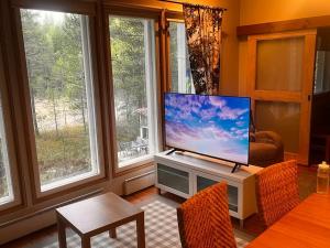 a living room with a flat screen tv on a stand with windows at Karhurinne Koli in Hattusaari