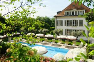 a resort with a pool and chairs and umbrellas at Hotel Angleterre in Lausanne
