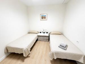 two beds in a room with white walls and wooden floors at Aroma D Valencia Luxury and Designer Apartment in Valencia