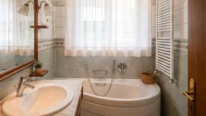a bathroom with a tub and a sink and a window at Appartamento Graziella in Castello di Fiemme +4 photos
