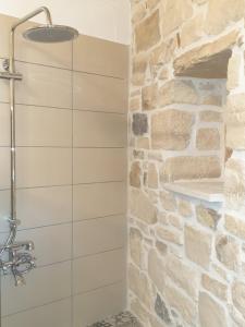 a shower in a bathroom with a stone wall at Villa Efthalia in Pitsidia +17 photos