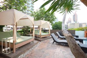 a patio with two beds and a palm tree at The Mandison Bangkok - Formerly Golden Tulip Mandison Suites in Bangkok