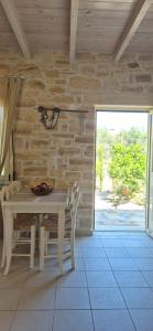 a table and chairs in a room with a stone wall at Villa Efthalia in Pitsidia