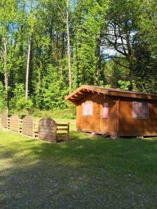 a wooden cabin with a fence in the grass at Pied de Mouton in Comblessac