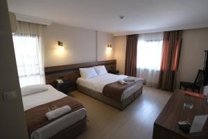 a hotel room with two beds and a table at Üstün Hotel Alsancak in İzmir