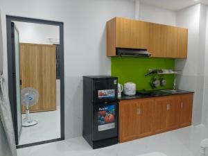 a kitchen with a refrigerator and a green wall at Phú Hưng Gia Motel in Ðức Hòa