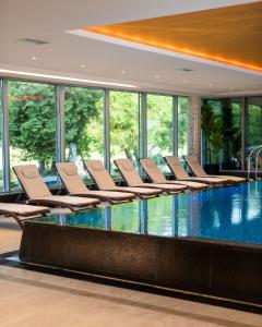a swimming pool with chairs in a building at Hotel Olympic Spa & Wellness in Ustroń