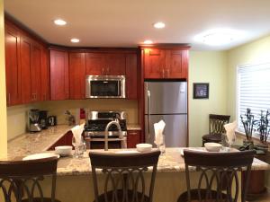 a kitchen with wooden cabinets and a kitchen island with bar stools at The Beach Palms Carlsbad in Carlsbad