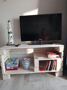 a television on a white entertainment center with books at SUPERBE VUE sur la MER in Le Grau-dʼAgde