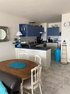 a kitchen with a wooden table and chairs and blue cabinets at SUPERBE VUE sur la MER in Le Grau-dʼAgde