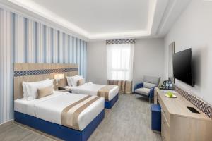 a hotel room with two beds and a television at Durrat Balensia Hotel - فندق درة بلنسية in Medina +15 photos
