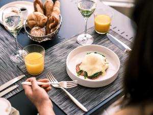 a table with a plate of food and glasses of wine at Falkensteiner Schlosshotel Velden – The Leading Hotels of the World in Velden am Wörthersee