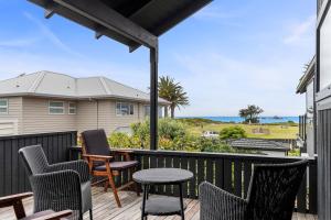 a deck with chairs and tables and a view of the ocean at Beachfront Marine Parade in Mount Maunganui