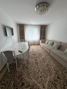 a living room with a table and a couch at Дом in Bishkek