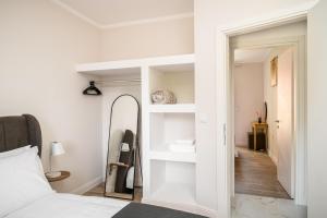 a bedroom with white walls and a bed and a mirror at Althaia Three-Bedroom Maisonette by Konnect in Corfu
