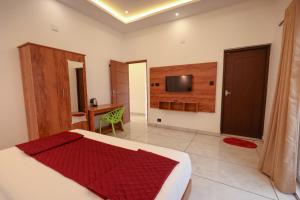 a bedroom with a bed and a desk and a television at Rivendell resort Munnar in Munnar