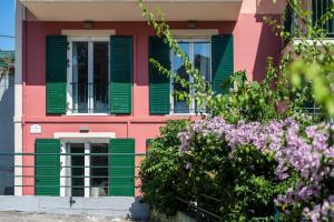 a pink building with green shuttered windows and purple flowers at Althaia Three-Bedroom Maisonette by Konnect in Corfu