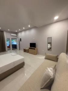 a bedroom with a bed and a couch and a tv at Fatses in Nea Plagia