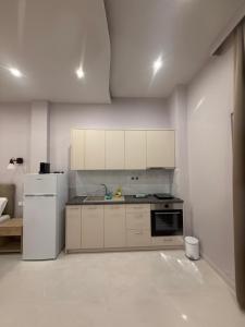 a kitchen with white cabinets and a stove and refrigerator at Fatses in Nea Plagia