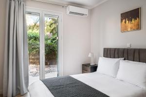 a white bedroom with a bed and a sliding glass door at Althaia Three-Bedroom Maisonette by Konnect in Corfu