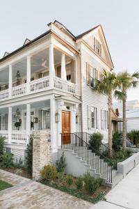 een wit huis met een veranda en palmbomen bij 86 Cannon Historic Inn - Adults Only in Charleston