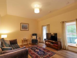 a living room with a couch and a television at Laundry Cottage in Strathpeffer