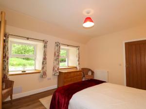 a bedroom with a bed and two windows at Laundry Cottage in Strathpeffer