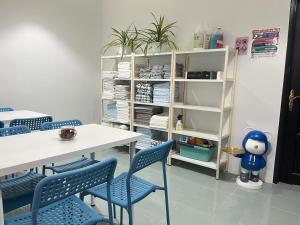 a room with blue chairs and a table and shelves at Dino House in Taiping