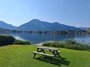 a picnic table sitting on the grass next to a lake at Seehäusl mit Badeplatz in Tegernsee +2 photos