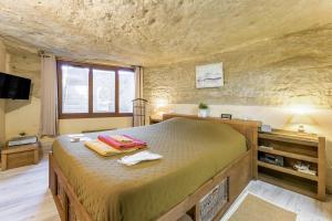 a bedroom with a large bed in a stone wall at Studio Troglodyte en Provence in Cornillon-Confoux