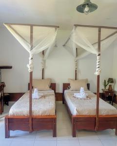 two beds in a room with two mosquito nets at Hotel Jardin de la Paix in Moroni +43 photos