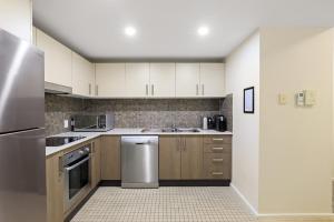 a kitchen with white cabinets and stainless steel appliances at Solara at Aqua Mantra in Nelson Bay