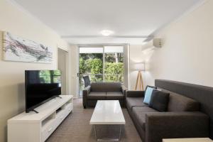 a living room with a couch and a tv at Solara at Aqua Mantra in Nelson Bay