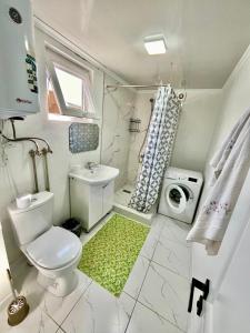 a bathroom with a toilet and a sink and a washing machine at Sunrise House in Cholpon-Ata