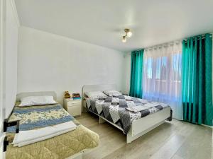 a bedroom with two beds and a window with blue curtains at Sunrise House in Cholpon-Ata