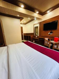 a bedroom with a large white bed and a flat screen tv at YogMaya Regency in Shimla +58 photos