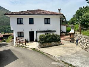 a white house with a garage on the side of a road at Casa El Acebal in Llanes