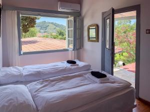 two white beds in a room with a window at LAGO Skiathos Guest Suites in Skiathos