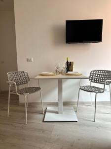a table with two chairs and a tv on a wall at Dimora di Aida Lugano Lake in Porlezza