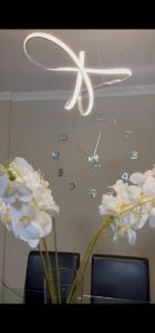 a clock on the wall with white flowers in a vase at Beach Apartment in Durban in Amanzimtoti