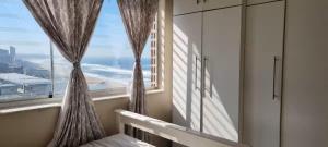 a bedroom with a window with a view of the ocean at Beach Apartment in Durban in Amanzimtoti