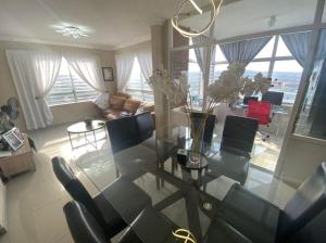 a living room with a glass table and chairs at Beach Apartment in Durban in Amanzimtoti