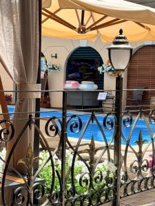 Ein schmiedeeiserner Zaun mit einem Pool im Hintergrund in der Unterkunft Hotel Otrada in Odessa